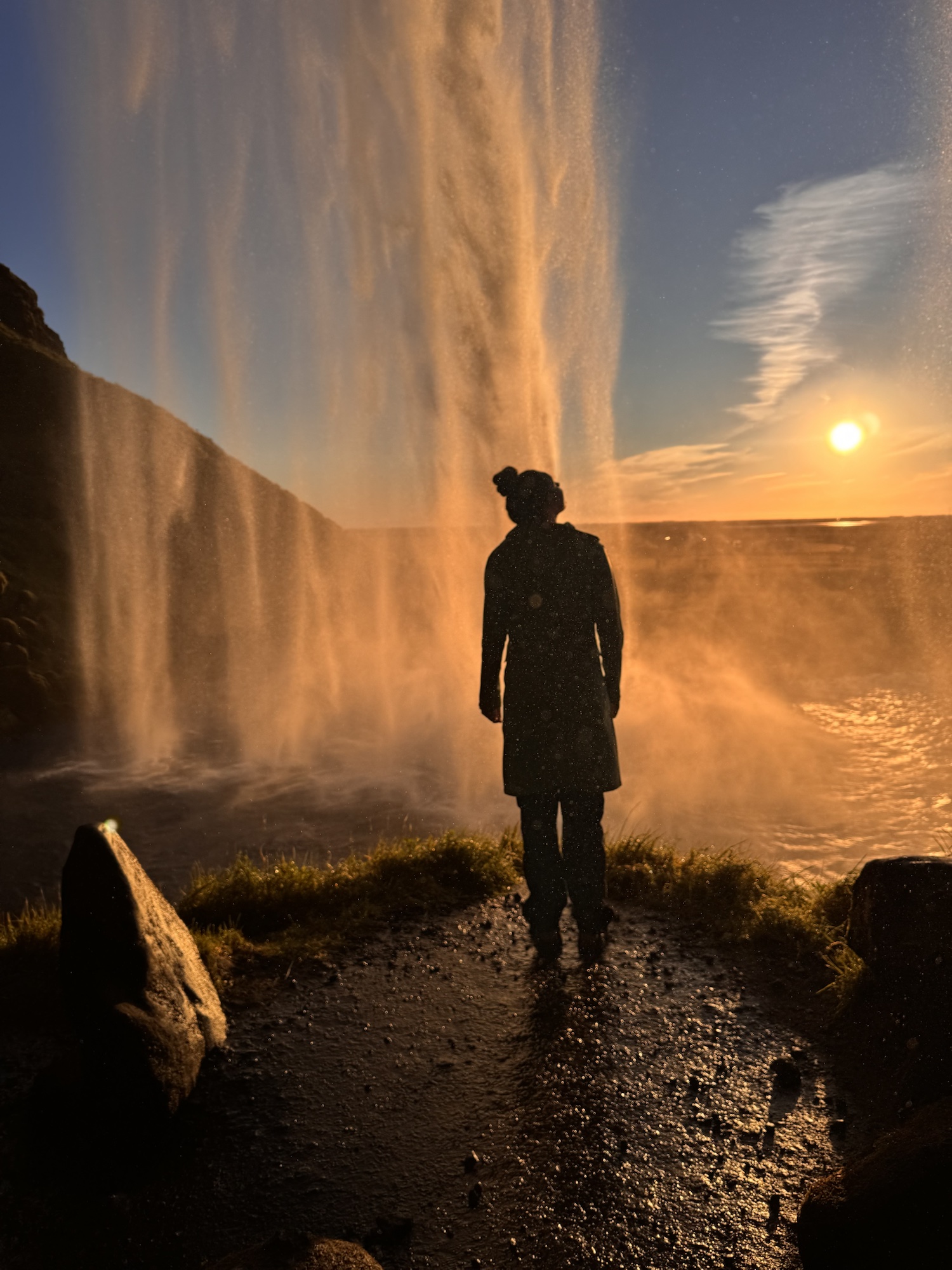 Paetan standing behind a waterfall at sunset